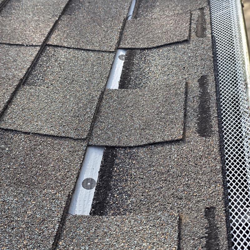Asphalt shingles with hail impact damage near gutter guard