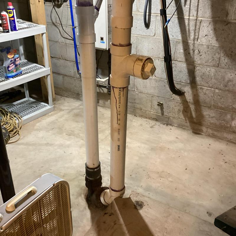 PVC drain pipes in basement near concrete wall