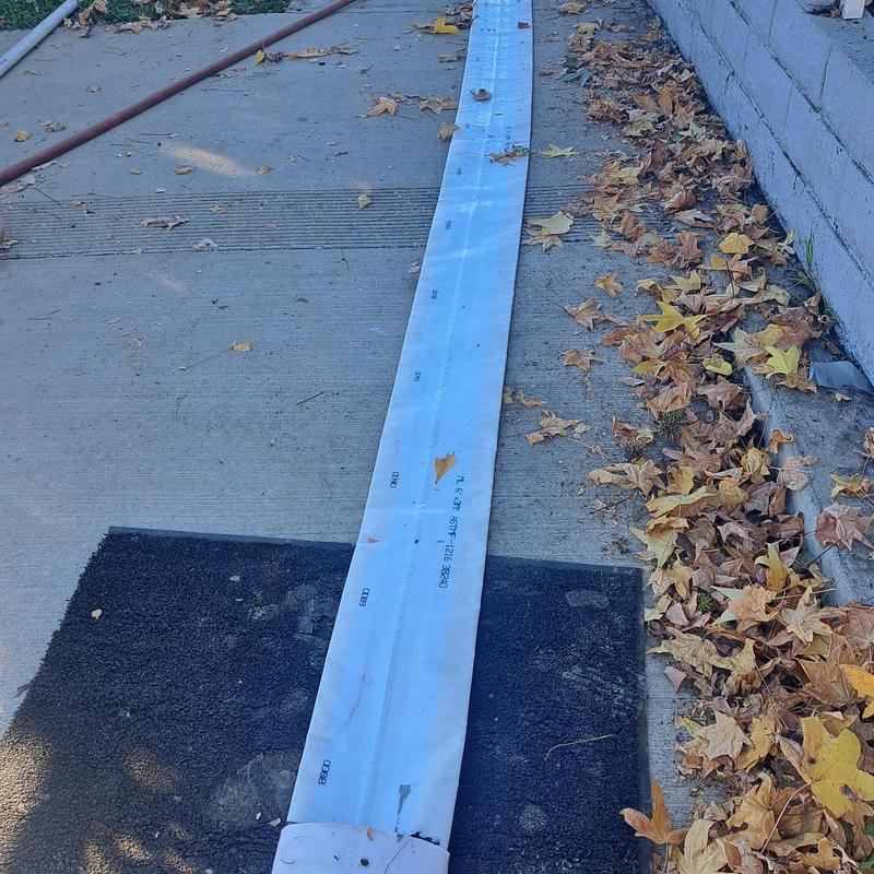 Sewer line replacement pipe laid on sidewalk near wall Sewer line replacement pipe laid on sidewalk near wall