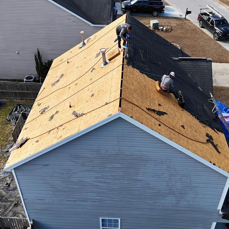 Roof decking replacement with workers installing felt underlayment