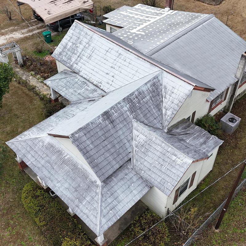 Metal roof inspection with visible storm damage overview