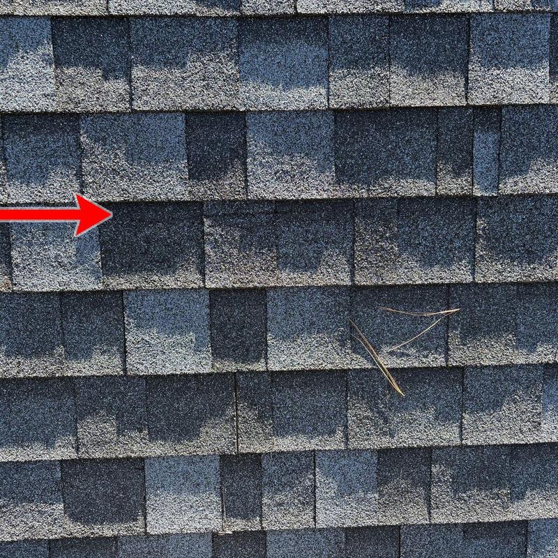 Asphalt shingles storm damage with red arrow indicator