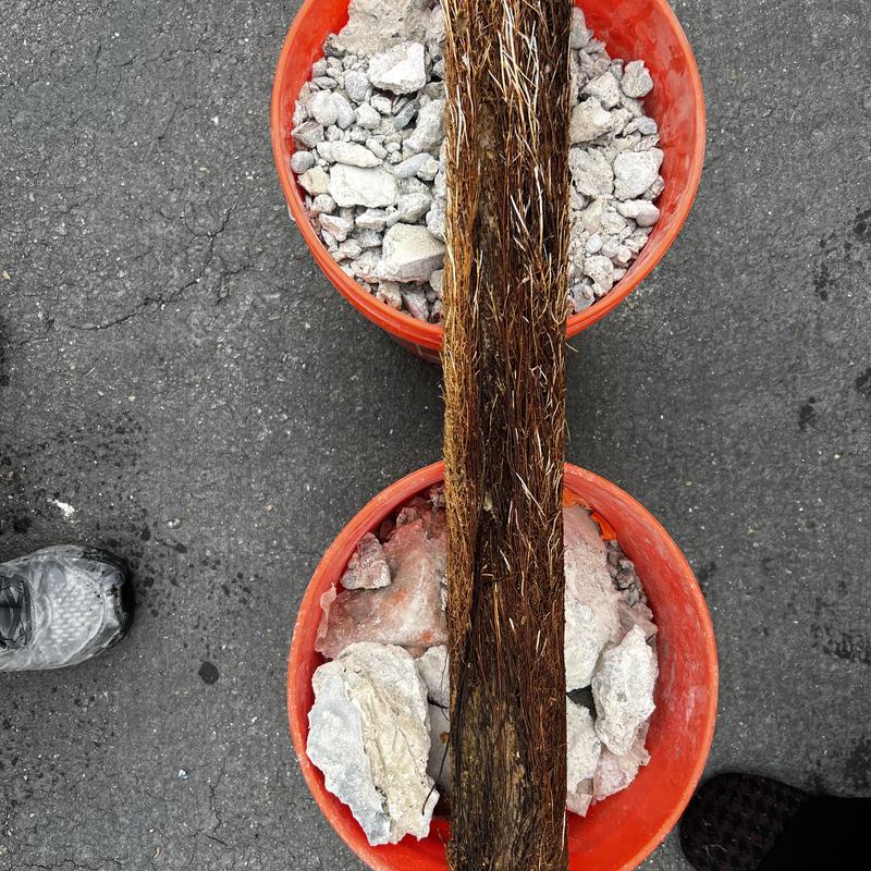 Toilet drain roots and broken concrete debris in buckets