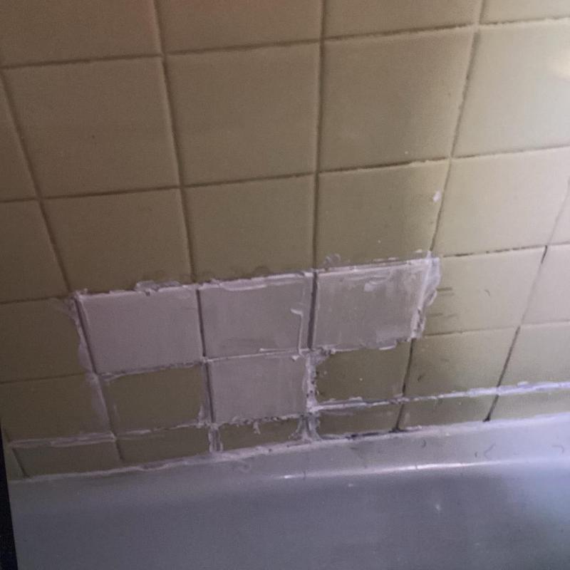 Cracked shower tile with patch repair on wall