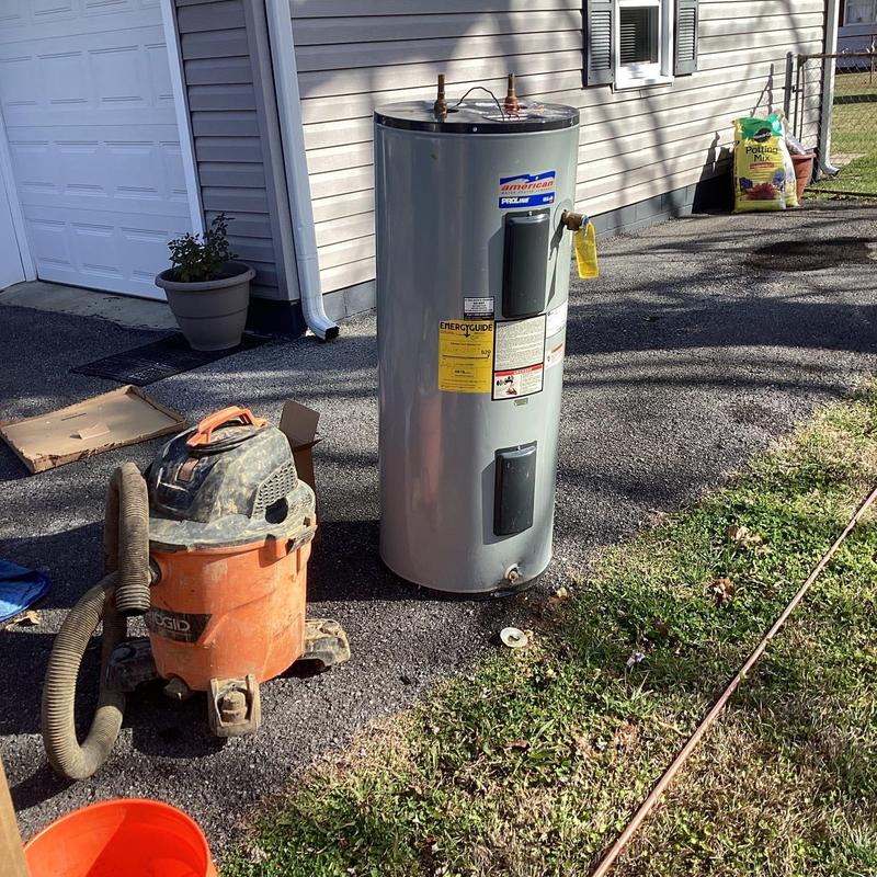 Water heater unit removed outdoors with vacuum nearby