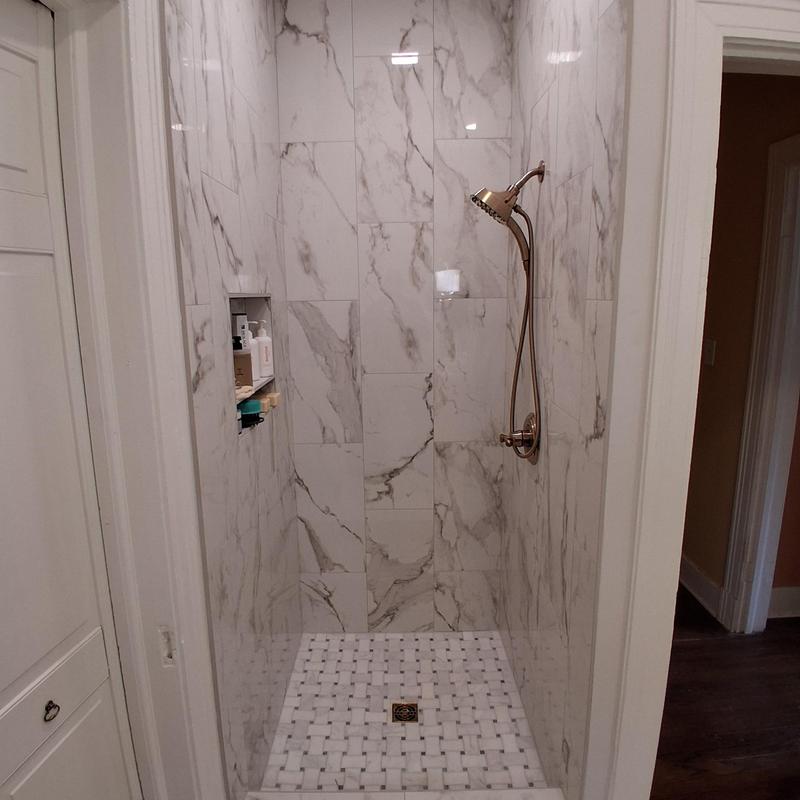 Marble tile shower with bronze showerhead and niche Marble tile shower with bronze showerhead and niche