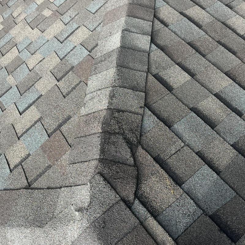 Asphalt shingle roof ridge with visible damage and wear