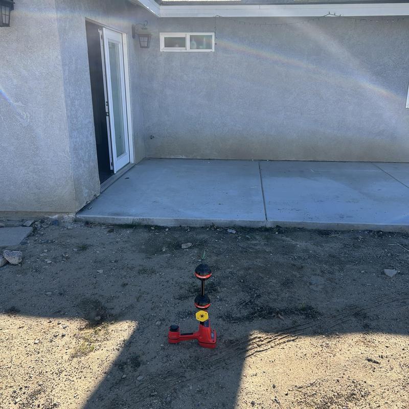 Concrete patio with marking tool on dirt ground