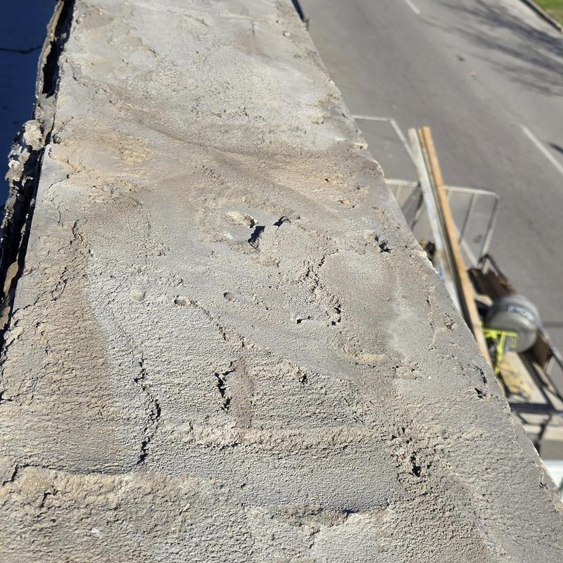 Concrete parapet wall with surface cracks and wear Concrete parapet wall with surface cracks and wear