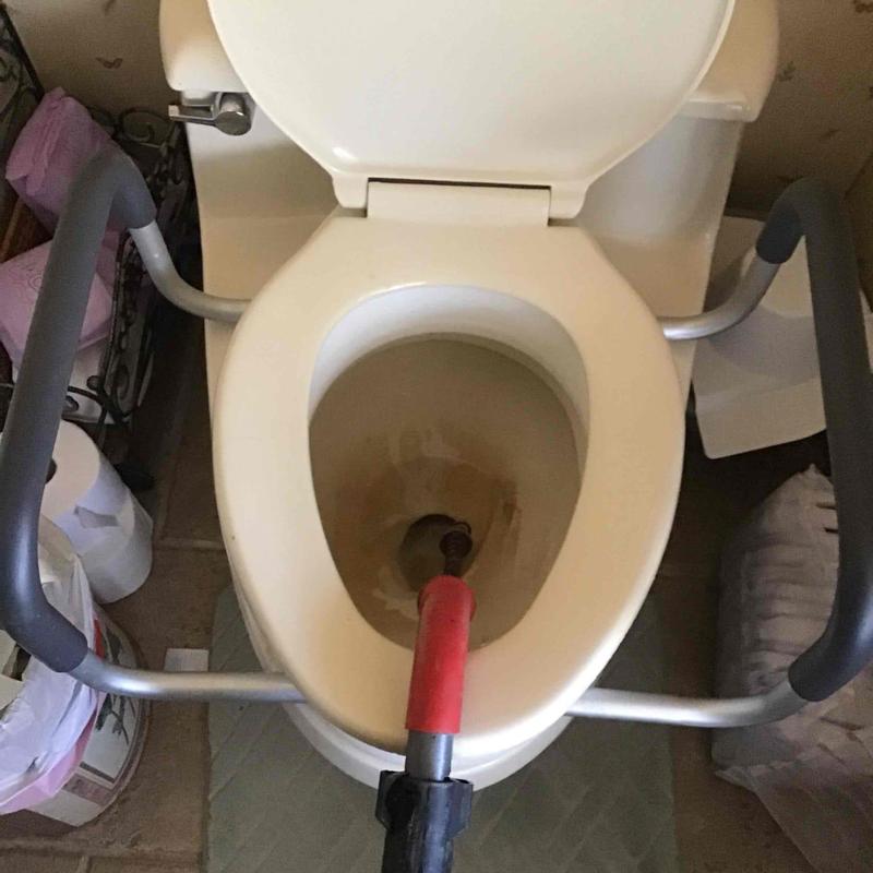 Toilet cabled with drain cleaning tool in bathroom