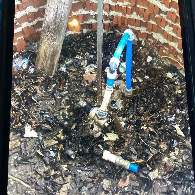 Water line and valve inside old brick well with debris