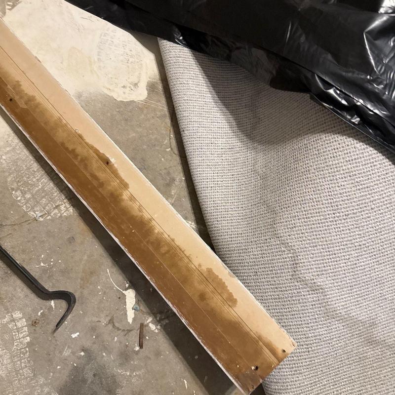 Carpet edge strip with water damage and debris nearby