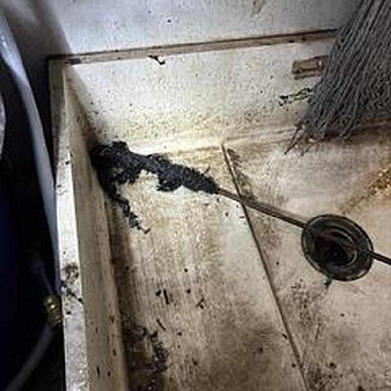 Mop sink drain with removed clog and cleaning rod