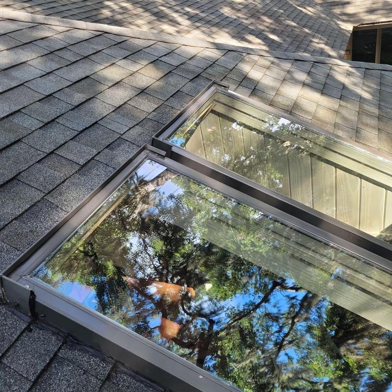 Skylights on shingle roof with reflective glass panels Skylights on shingle roof with reflective glass panels