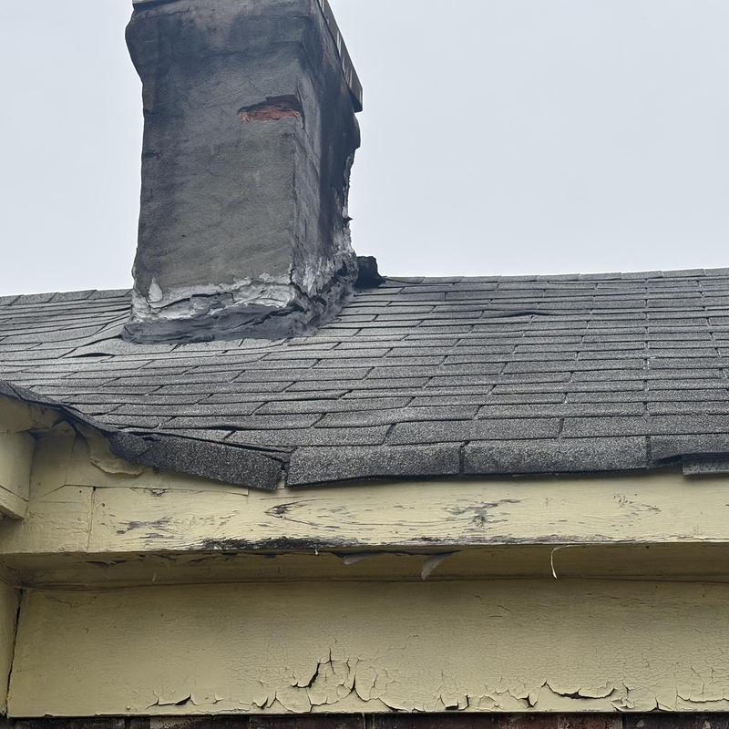 Chimney flashing and damaged shingle roof section