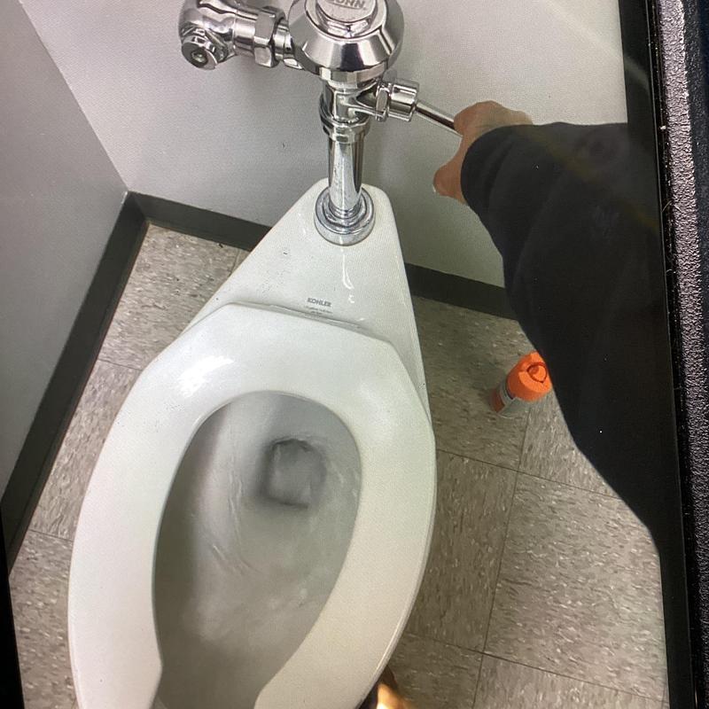 Women’s last stall commode flush valve adjustment in restroom