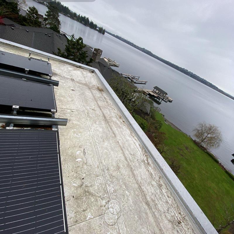 Flat roof surface with mounted solar panels near lake view