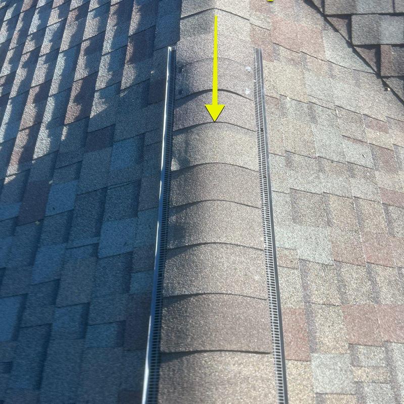 Ridge shingles with yellow arrow marking damage on roof Ridge shingles with yellow arrow marking damage on roof