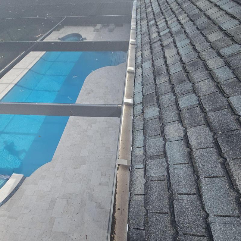 Gutter and downspout along shingled roof near pool enclosure Gutter and downspout along shingled roof near pool enclosure