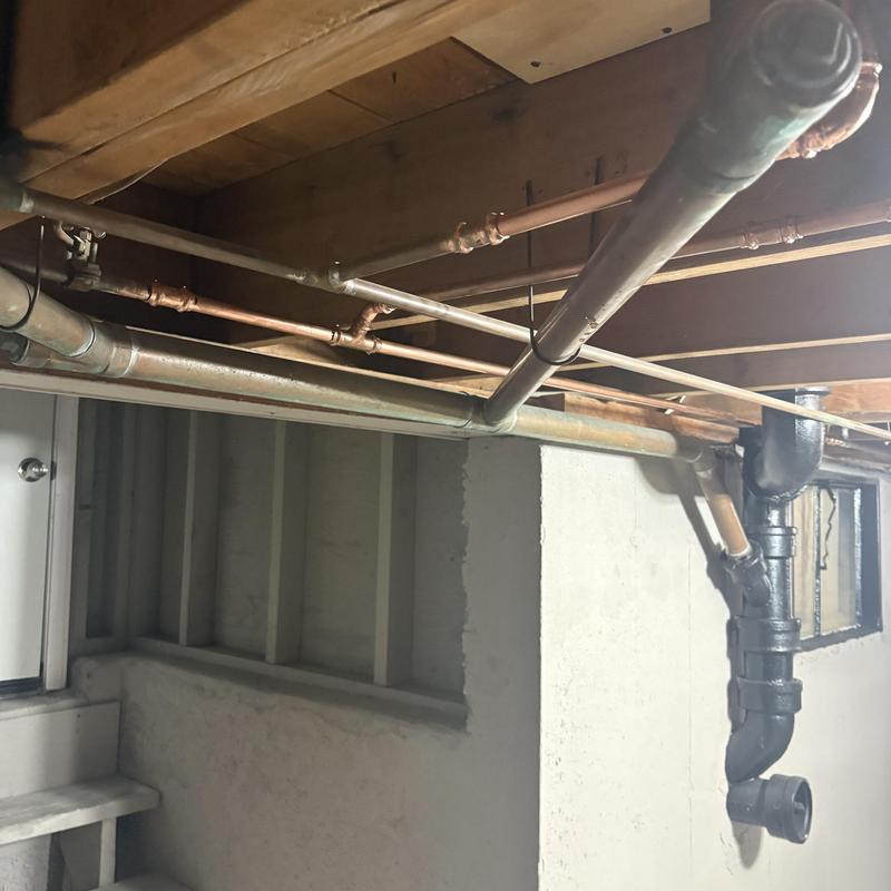 Copper water pipes and cast iron drain under floor joists