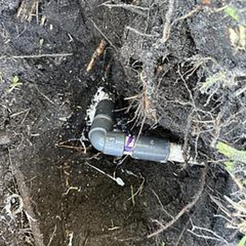 4-inch PVC sewer pipe with elbow joint in soil trench