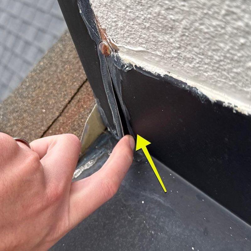 Flashing sealant gap at roof edge with finger pointing