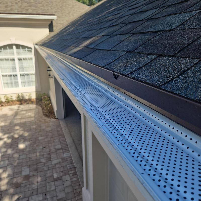 Gutter leaf guards installation on house roof edge Gutter leaf guards installation on house roof edge