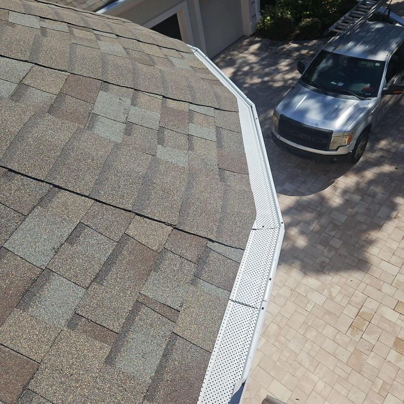 Gutter with new leaf guards on shingle roof edge Gutter with new leaf guards on shingle roof edge