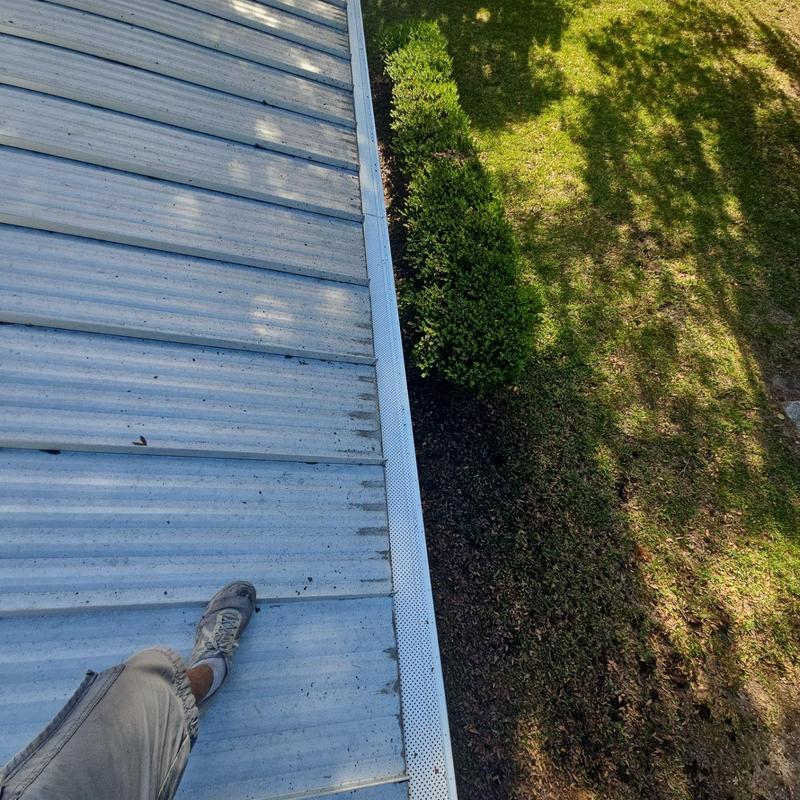 Leaf guard gutter along metal roof edge Leaf guard gutter along metal roof edge