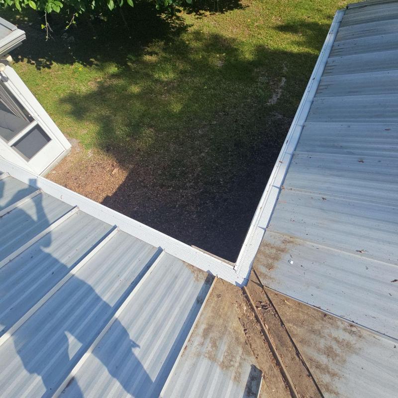 Leaf guard gutter installed on metal roof corner Leaf guard gutter installed on metal roof corner