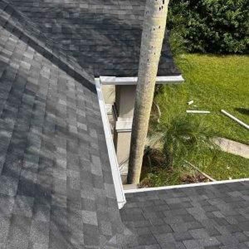 Asphalt shingle roof with white metal gutter installation Asphalt shingle roof with white metal gutter installation