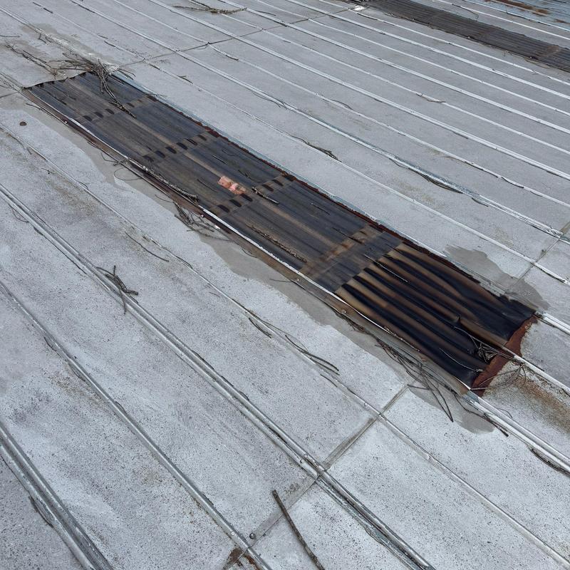 Metal roofing panel with corrosion and damage detail