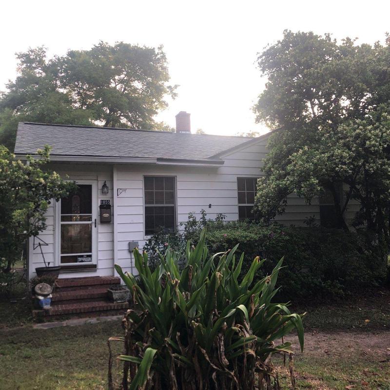 Asphalt shingle roof on single-story home with greenery Asphalt shingle roof on single-story home with greenery