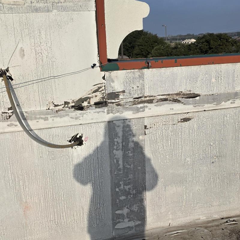 Roof parapet wall with hail damage and exposed conduit Roof parapet wall with hail damage and exposed conduit