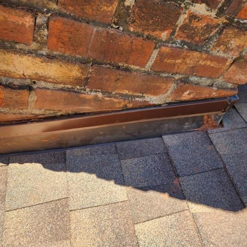 Metal step flashing installed on asphalt shingle roof and brick wall