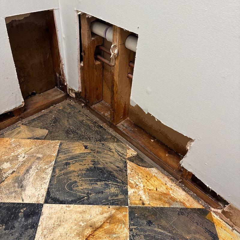 Wall plumbing pipes with water damage and floor removal