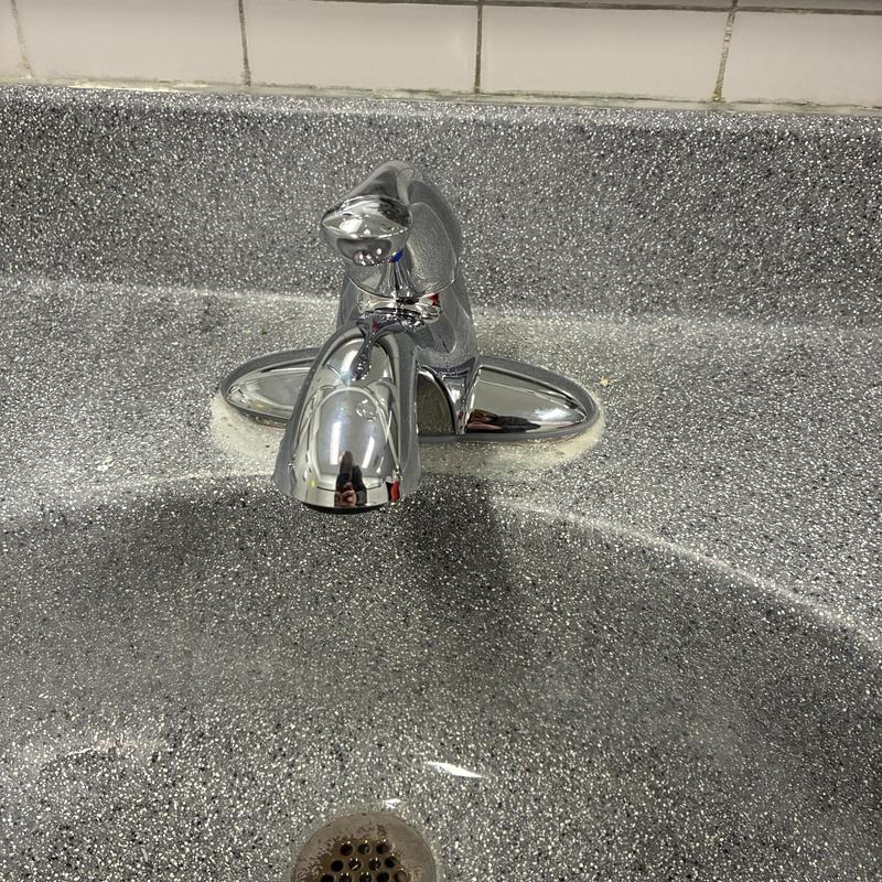 Lavatory faucet on speckled countertop, men's room
