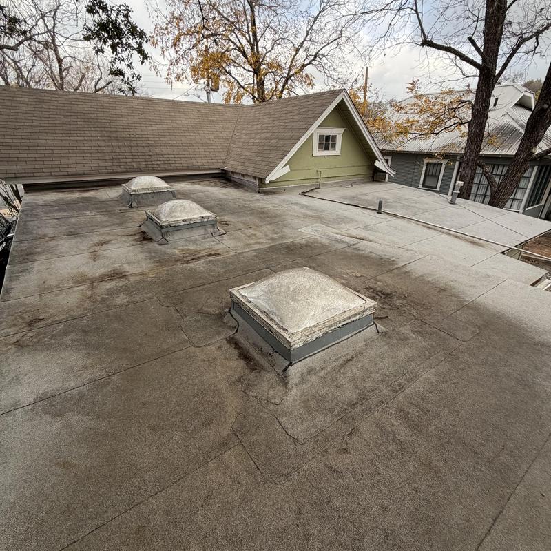 Modified bitumen flat roof with skylights and wear marks
