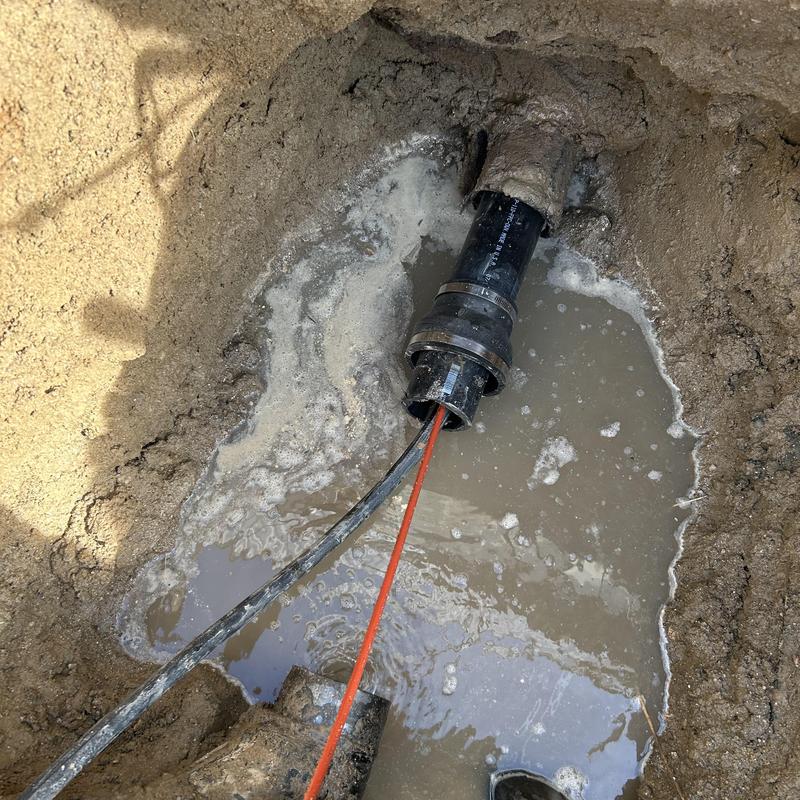 Broken underground drain pipe with flowing gray wastewater