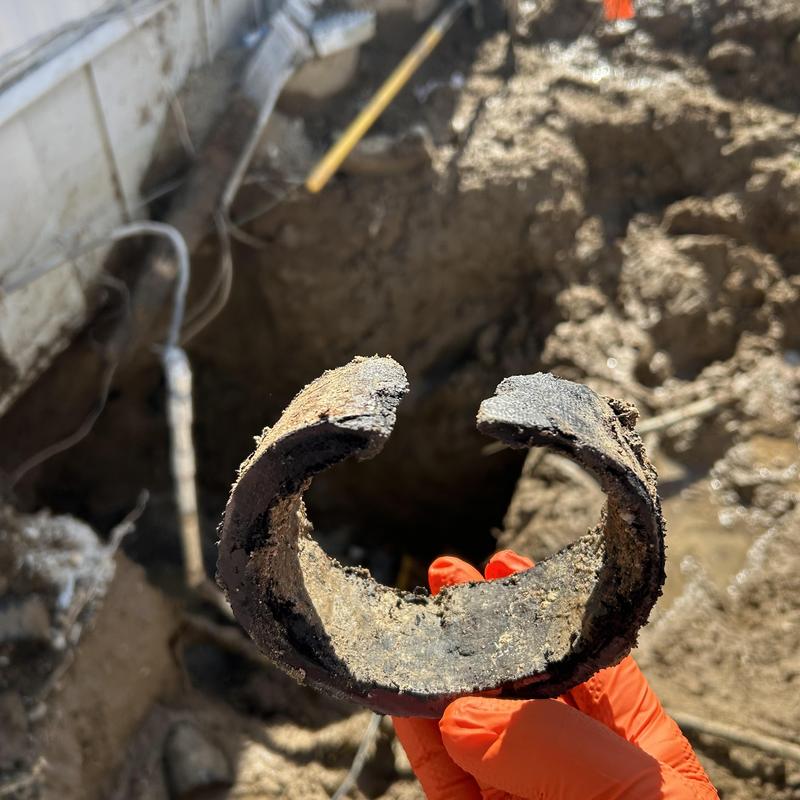 Deteriorated broken drain pipe section in excavation hole