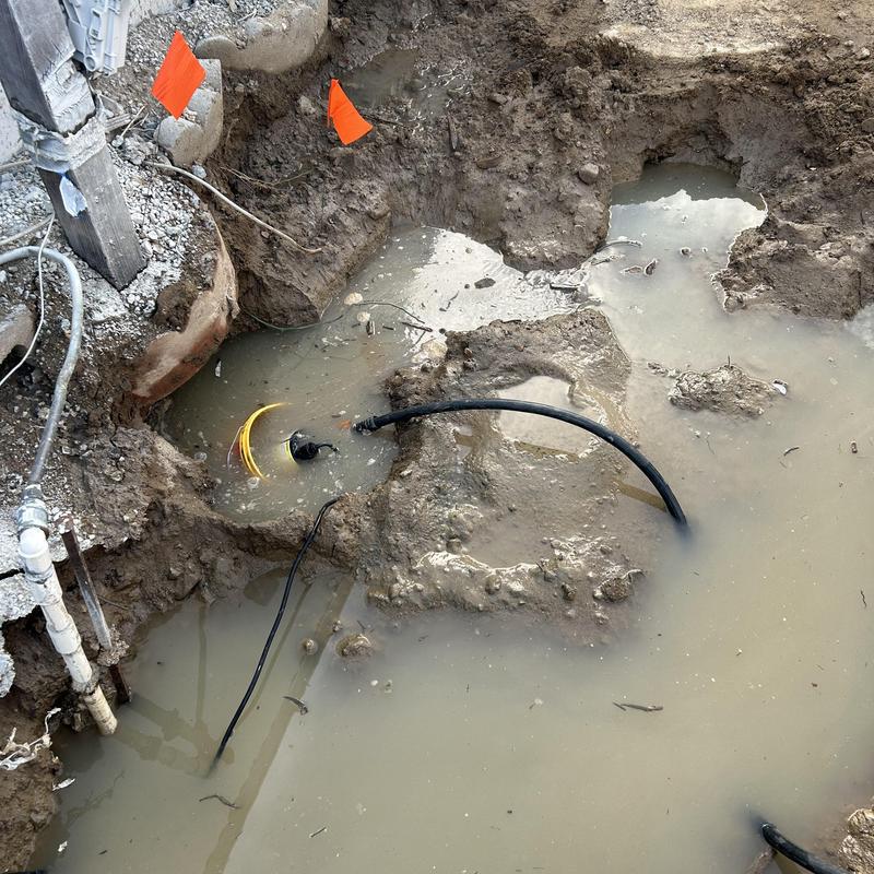 Broken underground drain pipe in muddy excavation site