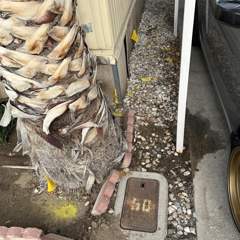 Underground water pipes with exposed rocky soil near driveway