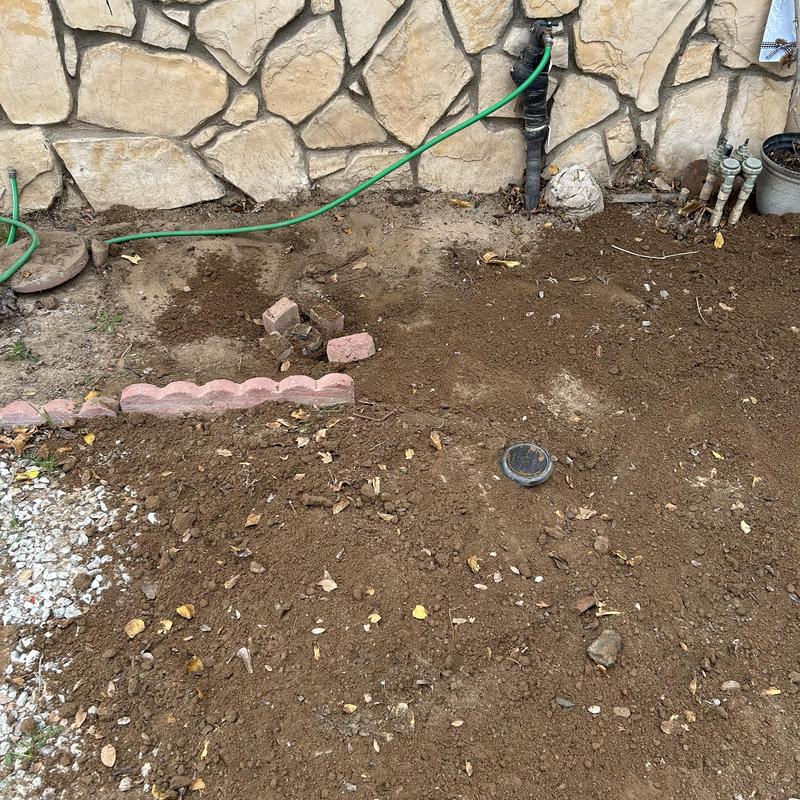 Drain pipe excavation with exposed valve and irrigation lines