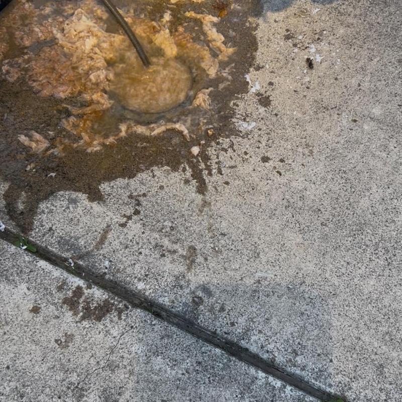 Main drain clog clearing using drain snake on concrete driveway