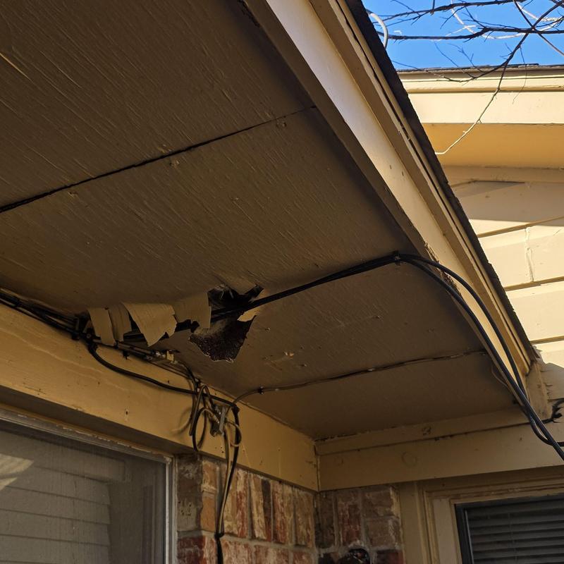 Soffit panel with hail damage hole and wiring