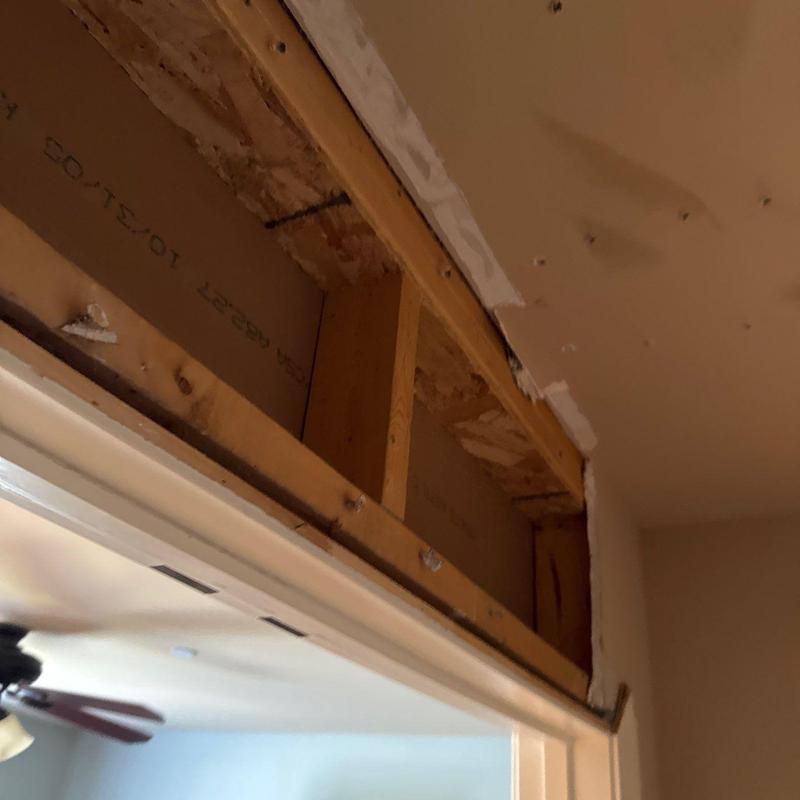 Drywall above interior door frame with exposed studs
