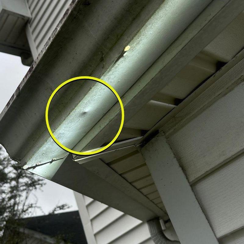 Metal gutter dent with hail damage, roof edge view