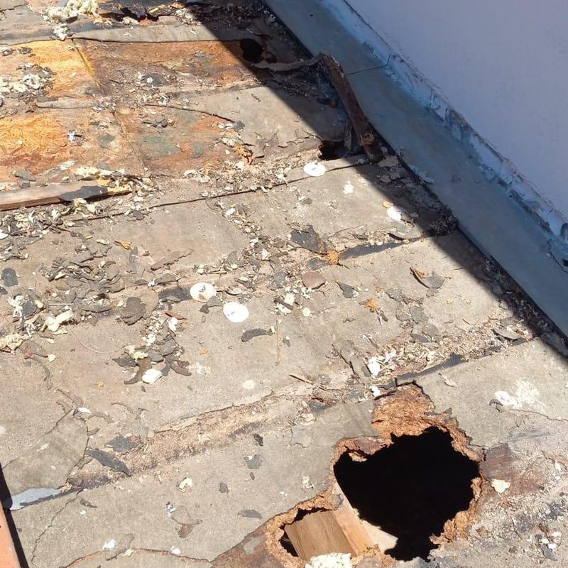 Roof decking hole with water damage near sidewall flashing