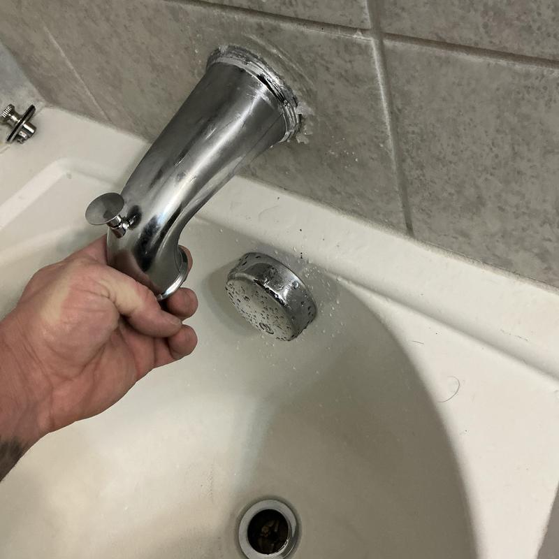 Tub spout installation on bathtub with hand holding spout