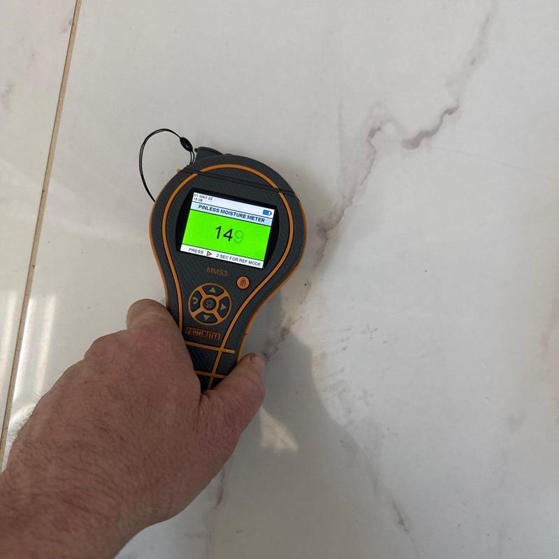 Moisture meter testing on tile floor surface